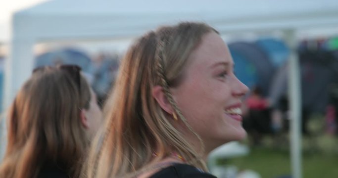 Smiling caucasian girls walking at festival camping site in slow motion 