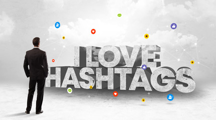 Young businessman standing in front of I LOVE HASHTAGS inscription, social media concept