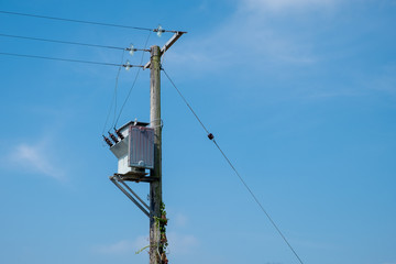 A small pole-mounted electrity transformer against a blue sky in England, UK