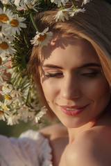 Closeup portrait of a beautiful blonde in a chamomile field.