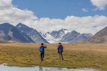 Fototapeta na wymiar Tourists relax near the lake and enjoys beautiful views of the mountains of the Mongolian Altai