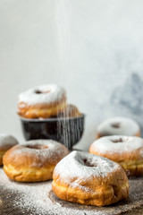 Lush sweet homemade donuts sprinkled with powdered sugar on a wooden background