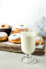 tasty sweet homemade donuts with a mug of milk on a wooden background