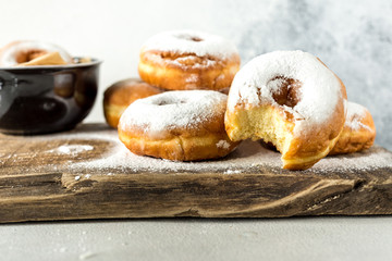 Lush sweet homemade donuts sprinkled with powdered sugar on a wooden background