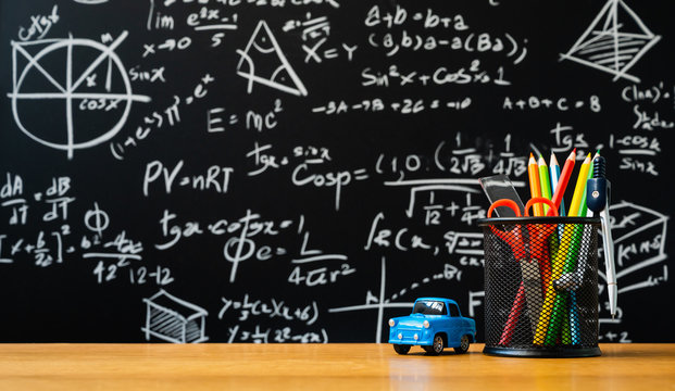 Education background concept. Stationery in holder color pencil, compasses tool, scissors, rulers, car toy On chalkboard with the Mathematical formula background.