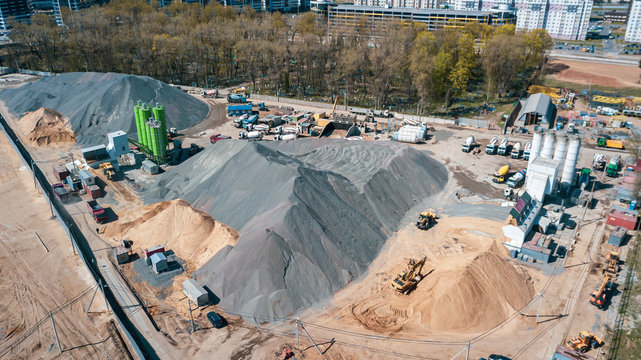 Aerial view of concrete and cement mortar plant. Concrete mixing silo for stone and sand. Bulk material storage site. Industrial concept and construction background.