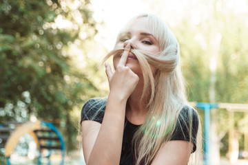 Beautiful blond girl with long hair on playground with blurred background.