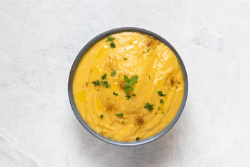 Vegetarian red lentil creamy soup with pumpkin and potatoes in a bowl decorated with marjoram on...