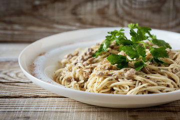 macaroni with mushrooms and fresh herbs close up in a plate on a wooden background