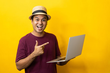 Asian man red shirt with hat using laptop on isolated yellow background.