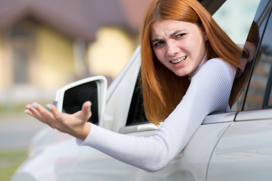 Closeup Portrait Of Pissed Off Displeased Angry Aggressive Woman Driving A Car Shouting At Someone With Hand Up. Negative Human Expression Consept.