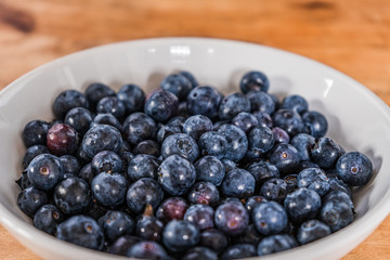 Fresh blueberries in a white bowl on a wooden table