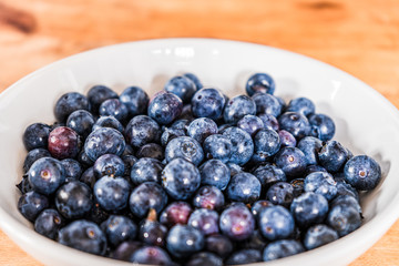 Fresh blueberries in a white bowl on a wooden table