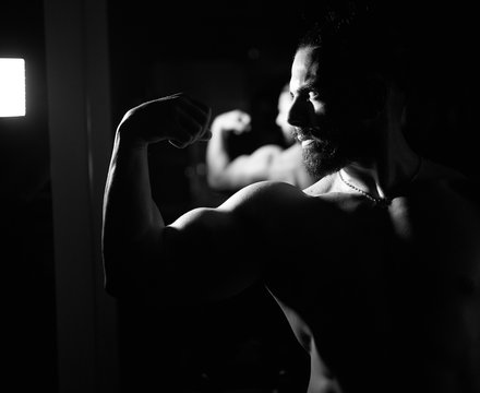 black and white picture of muscular young man in the dark, portrait of a young man in the dark
