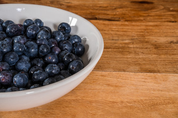 Fresh blueberries in a white bowl on a wooden table