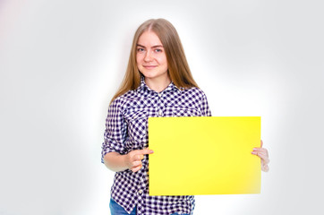 Obraz na płótnie Canvas A young girl in a plaid shirt with long hair holds a large sheet, a frame for text in front of her, above herself, from the side. The girl demonstrates, offers, points
