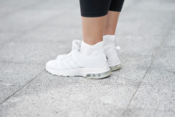 Closeup of female legs in stylish white sneakers. Active woman on a training. Ready to start.