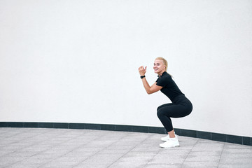 Obraz premium Young attractive sporty girl wearing black sportswear training on white wall background. Concept active and healthy life.