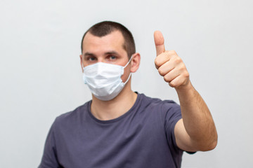 man in medical mask on his face showing thumb up on a white background.