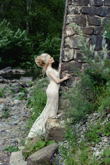 beautiful blonde in a wedding dress on the nature near the rocks