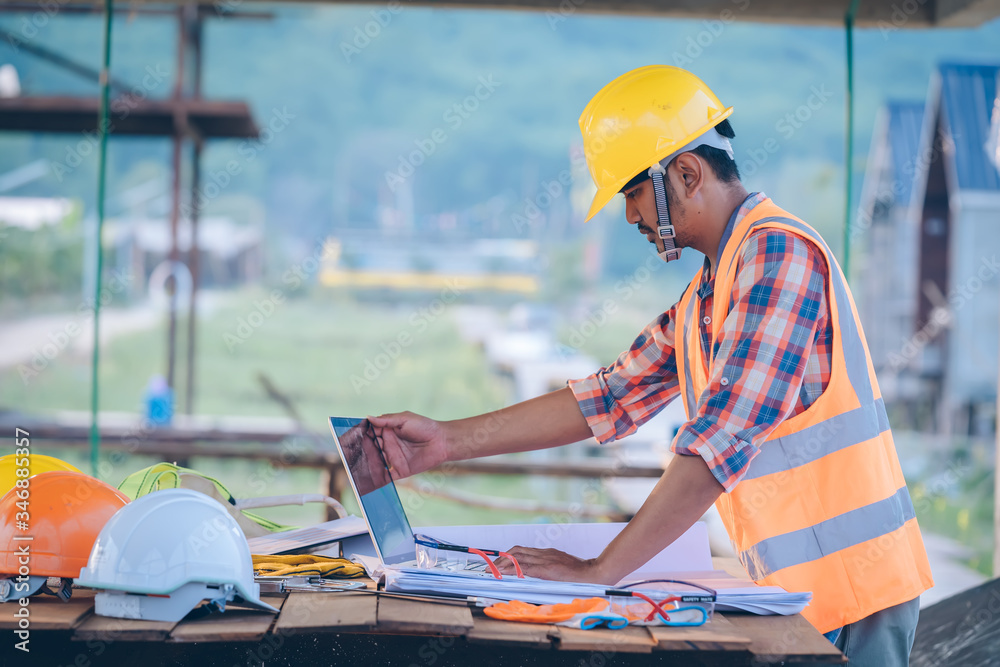 Poster Engineer working with laptop and blueprints,engineer inspection in construction site for architectural plan,sketching a construction project.