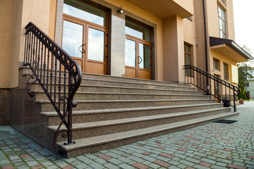 Detail of a house facade. New granite stairs with metal railings.