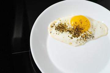 fried chicken egg on a white plate on a black background