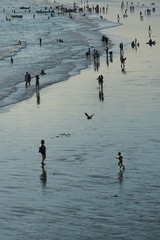 People on the beach.  Silhouette of a child running to his mother. 