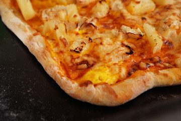 Close up hawaiian pizza - simple homemade Hawaiian pizza on a black baking sheet