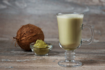 Matcha Latte with coconut milk in a glass mug on a wooden background