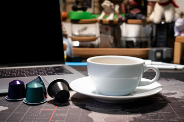 A cup of Black coffee and capsules on the world map