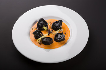 Black ravioli pasta with orange sauce