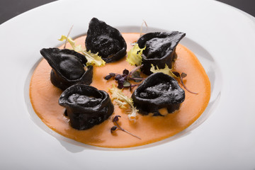 Black ravioli pasta with orange sauce