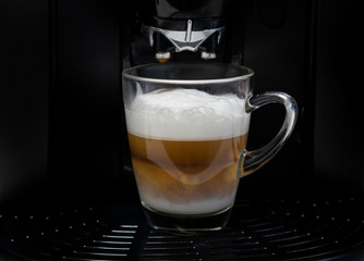 Making cappuccino coffee with black espresso machine