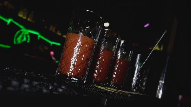 Highball glasses of alcoholic cocktail Bloody Mary are on the bar stool or tab in night club. Young lifestyle and relaxing in holidays concept. Dutch angle hand held shot