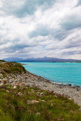 Fototapeta na wymiar Mountains over turquoise water. Trek towards the Southern Alps and Mount Cook, New Zealand