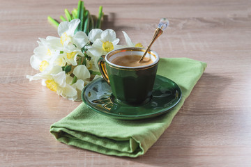 Vintage cup of coffee with beautiful spoon and bouquet of white daffodils