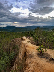 Sanstone path walk way down hill trees rain forest pai canyon dark sky sunshine light through clouds orange mountain