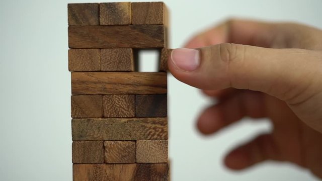 Business risks concept. Hand pulls out wooden brick with jenga game. jenga falls