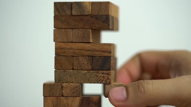 Business risks concept. Hand pulls out wooden brick with jenga game. jenga falls
