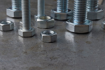 Bolts and hex nuts of various sizes, laid out on a metal surface. assorted closeups.