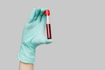 hand holding blood in test tube close up over light gray background