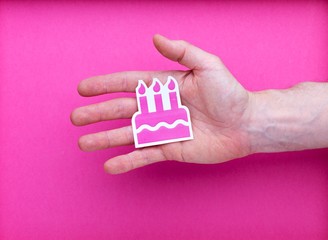 Symbole fête illustration dessin gâteau rose anniversaire dans main ouverte homme isolé sur arrière-plan rose