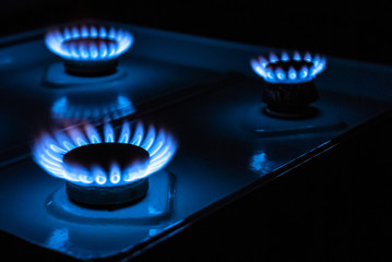 Blue flames on three gas stove burners in the darck