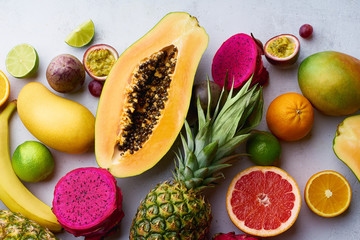Flat lay tropical exotic fruits. Healthy summer food ingredients: papaya, pitaya, pineapple, orange, lime, grapes and mango.