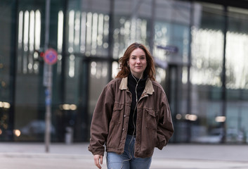 Young Woman in Brown Jacket Walking and Smiling at Camera