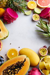 Flat lay tropical exotic fruits with copy space. Healthy summer food ingredients: papaya, pitaya, pineapple, orange, lime, grapes and mango.