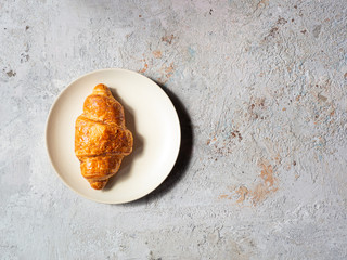 french croissant on beige plate, textured background, top view, copy space