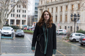 Fototapeta premium Young Woman Wearing Black Coat Posing in City