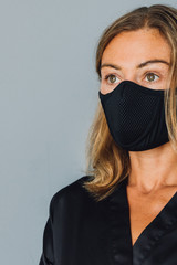 Portrait of a young woman in a black mask , during isolation, stay at home, look to the side